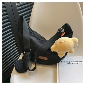 Detail of black corduroy crescent crossbody bag with mini coin purse and plush charm