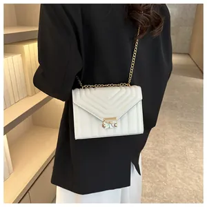 Detailed view of a white quilted crossbody bag with gold chain strap and stud buckle