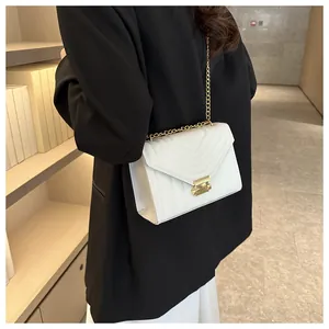 Detailed view of white quilted crossbody bag with gold chain strap on black blazer