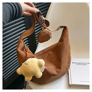 Detail of coffee brown corduroy crescent bag with mini coin purse and plush croissant charm