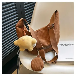 Detail of brown corduroy hobo bag featuring a wide strap and a small round coin purse