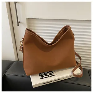 Close-up of brown suede hobo bag with smooth gold-tone metal hook and slim shoulder strap