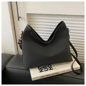 Detail of black matte nylon shoulder bag featuring a unique V-shaped opening and gold buckle