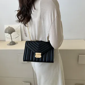 Elegant black quilted shoulder bag with gold chain strap shown on model in modern room