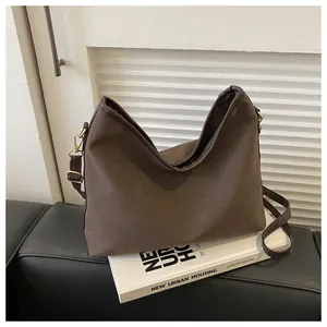 Detailed close-up of dark brown fabric tote bag with leather trim and gold hardware