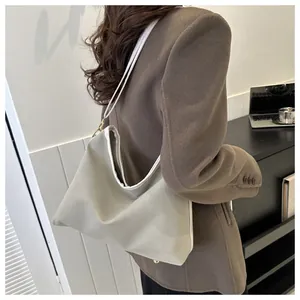 Sage green shoulder bag with white contrast edging and gold hardware worn with a brown coat