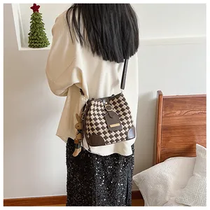Detail of vintage knit bucket bag featuring brown plaid pattern and plush rabbit charm