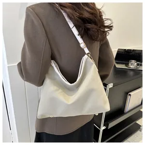 Detail of adjustable strap and gold metal buckles on a minimalist cream tote bag
