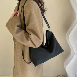 Chic black nylon tote bag on model shoulder with elegant gold hardware accents