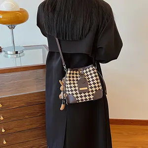 Checkerboard knit bucket bag with leather straps and cute plush pendant accessory