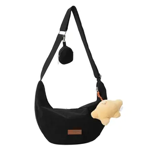 Black corduroy crescent crossbody bag with mini purse and star pendant on white background