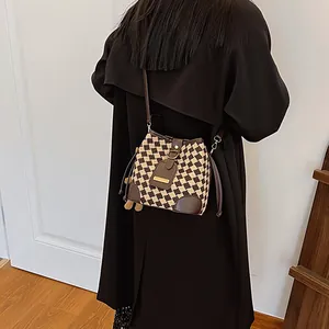 Brown and beige checkerboard knit bucket bag with leather strap and drawstring closure