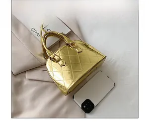 Detailed size comparison of the gold shell bag with a smartphone on a beige suit