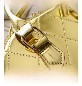 Close-up of golden metallic shell bag featuring quilted stitching and glossy hardware