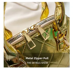 Close-up of golden shell bag hardware featuring dual zippers and rectangle metallic pulls