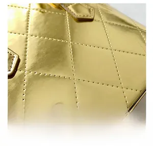 Detailed close-up of golden patent leather shell bag with quilted diamond stitching