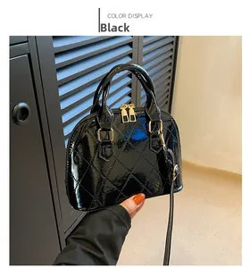 Close-up of black patent leather shell bag with quilted texture and gold hardware details