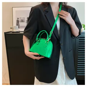 Model shot of green shell-shaped bag with diamond quilting and glossy metallic finish