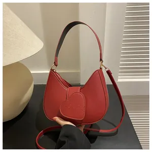 Macro detail of red crescent handbag featuring heart flip-cover and embossed LOVE text