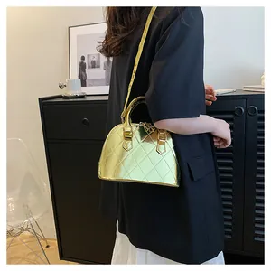Model wearing a metallic gold quilted shell bag with polished mirror finish and top handles