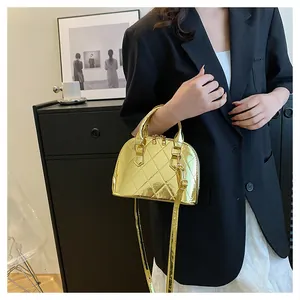 Detail view of gold shell bag with patent leather finish and quilted rhombus pattern