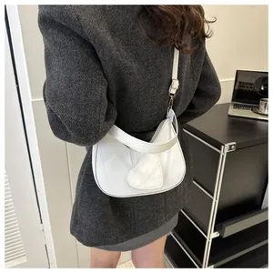 Close-up of white half-moon shoulder bag featuring a heart patch and LOVE engraving