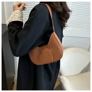Side view of a brown half-moon shoulder bag with a heart-shaped LOVE flap on a model