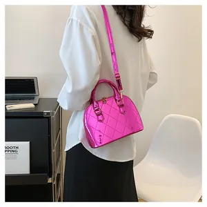 Detail of pink metallic shell bag with glossy finish and adjustable shoulder strap