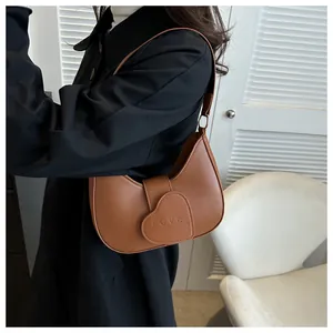 Brown leather crescent bag with heart-shaped LOVE buckle shown on a shoulder model