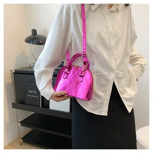 Magenta glossy shell bag with rhombus quilting and shoulder strap on model