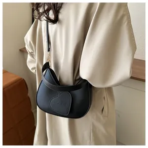 Detail of black half-moon crossbody bag featuring heart-shaped LOVE pendant and gold hardware