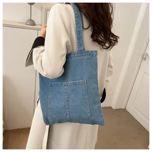 Détail du sac cabas en denim bleu avec deux poches avant et une large bandoulière