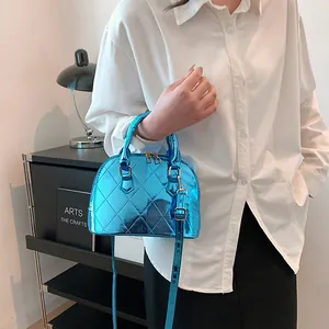 Glossy blue metallic shell bag with quilted texture and golden hardware shown on a model