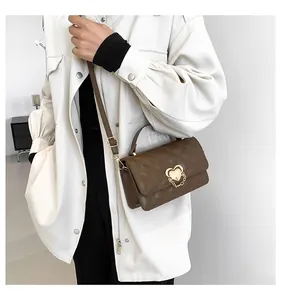 Detail der dunkelbraunen Stepptasche mit goldenem Herzverschluss und Kettenakzenten