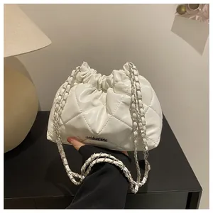 Détail du sac seau blanc matelassé avec bandoulière chaîne et plaque métallique gravée