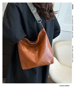 Detail view of large brown leather tote featuring a colorful ethnic woven shoulder strap