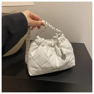 Détail du sac seau matelassé blanc avec fermeture à cordon et bandoulière chaîne