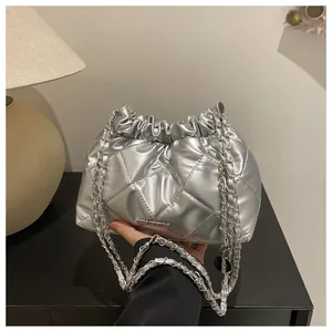 Gros plan détaillé d'un sac seau matelassé argenté avec une bandoulière chaîne chic