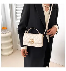 Elegante weiß gesteppte Umhängetasche mit goldenem Herzverschluss, getragen von einem Modell