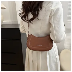 Sac hobo marron en cuir avec texte blanc porté à l'épaule par un mannequin