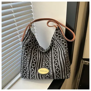Détail du sac cabas tissé noir et blanc avec bandoulière en cuir marron et boucle