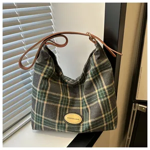 Détail d'un sac cabas à carreaux avec bandoulière en cuir et étiquette tendance