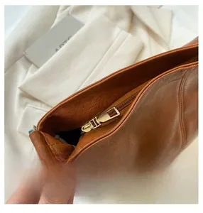 Detailed close-up of smooth gold metal zipper on vintage brown leather tote bag