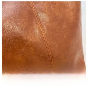 Detail of brown leather handbag featuring high-quality lychee texture and fine double stitching