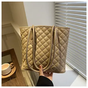 Close-up of beige quilted tote bag showing rhombus texture and long shoulder straps