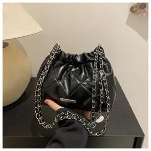 Détail du sac seau noir matelassé avec bandoulière chaîne argentée et logo métal