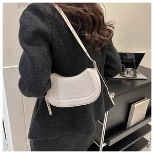 Gros plan d'un sac à bandoulière blanc en forme de croissant avec logo embossé