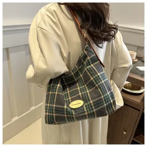 Détail du sac cabas à carreaux avec patch logo en cuir et fines anses marron
