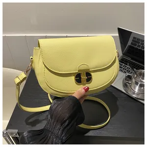 Close-up of bright yellow saddle bag featuring pebble leather and gold oval twist lock