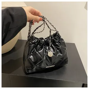 Détail du sac seau matelassé brillant avec poignée chaîne argentée et logo métallique